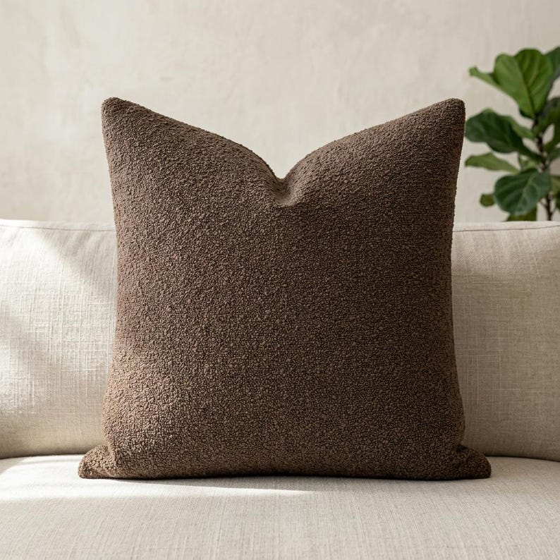 Brown boucle throw pillow cover styled on cream linen sofa with fiddle-leaf fig plant