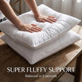 White down alternative pillow inserts stacked on a wooden table, hands pressing for super fluffy support. Soft,...