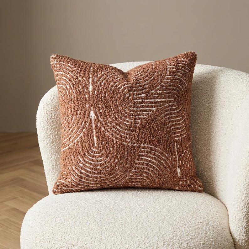 Tufted burnt orange chenille pillow cover styled on white bouclé armchair