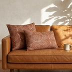 Set of 2 tufted burnt orange chenille pillow covers on tan leather sofa — square and lumbar sizes