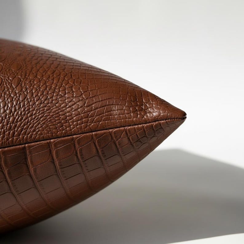 Close-up of hidden zipper edge on brown vegan leather crocodile embossed pillow cover