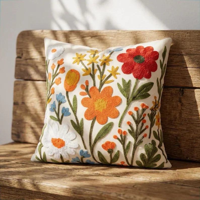 Wildflower embroidered pillow cover leaning on rustic wood bench — handcrafted cottagecore accent pillow