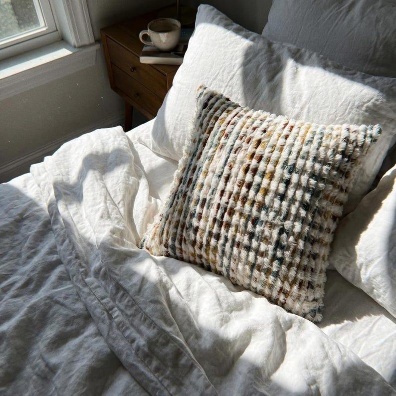 Artisan chenille tufted throw pillow cover styled on a white linen bed in a natural light bedroom setting
