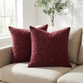 Set of 2 burgundy chenille throw pillow covers styled on a beige sofa in a bright living room