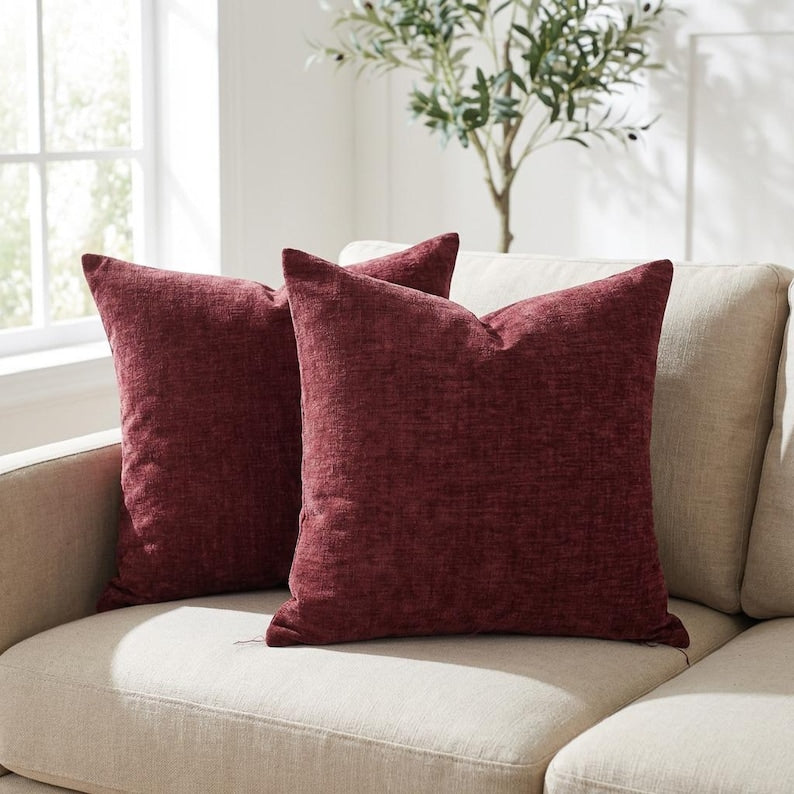 Set of 2 burgundy chenille throw pillow covers styled on a beige sofa in a bright living room