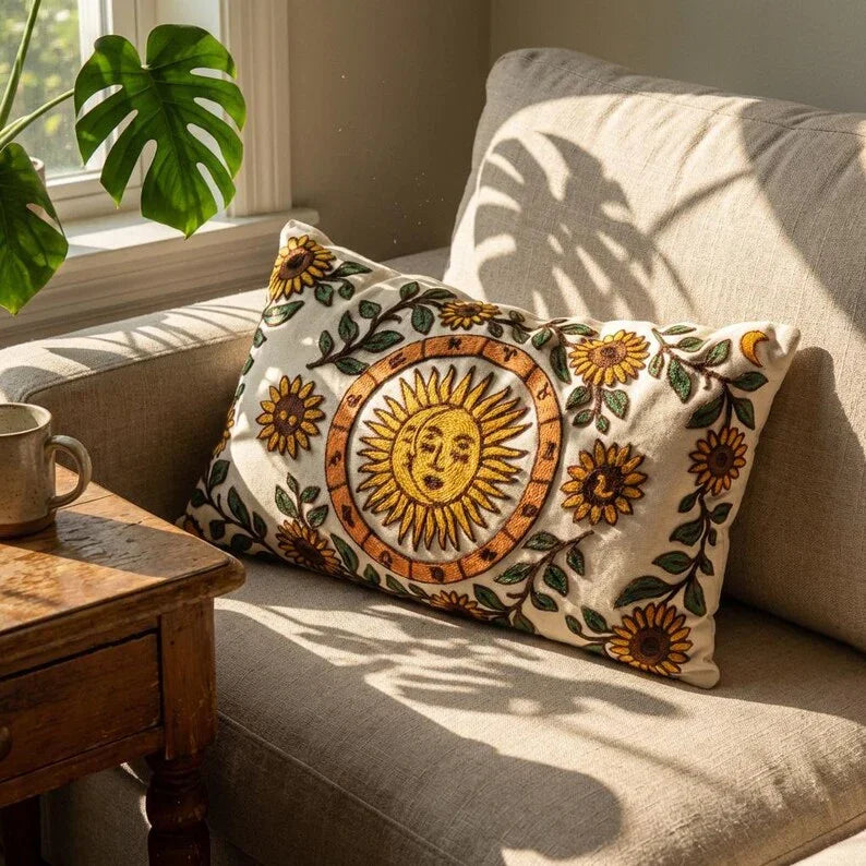 Celestial sun embroidered cotton canvas pillow cover with sunflower vines, styled on a neutral sofa in natural light