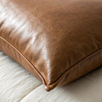 Corner detail of cognac brown vegan leather pillow cover showing hidden zipper and aged leather texture