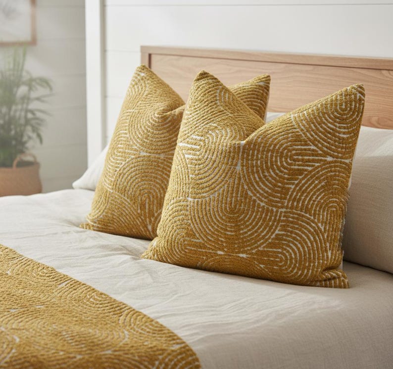 Yellow patterned pillows on a bed with a neutral background