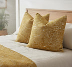Yellow patterned pillows on a bed with a neutral background