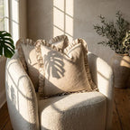 Two linen ruffle pillow covers styled on a boucle armchair in a bright living room