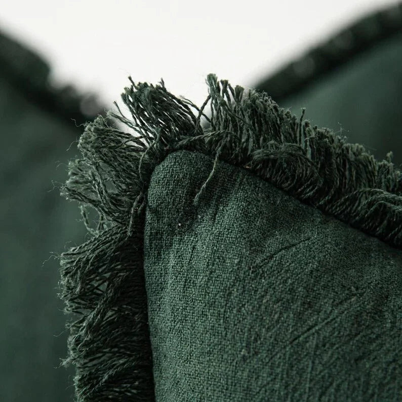 Close-up of linen fringe trim corner detail on olive green pillow cover showing slub texture and handcrafted edge