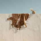 Faux cowhide area rug in brown and white draped over white wall in Mediterranean setting – Larissa Home Decor