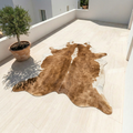Vegan leather cowhide rug in brown and white displayed on light tile floor outdoors – Larissa Home Decor