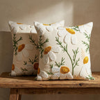 Pair of daisy floral punch needle pillow covers displayed on a rustic wooden bench