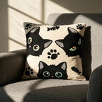Artisan embroidered cat pillow cover with green-eyed black cats on an armchair in natural light