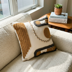 Handcrafted abstract boho tufted cotton pillow cover in mustard and charcoal, lifestyle shot on boucle couch with books