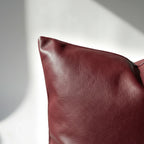 Corner detail of burgundy faux leather pillow cover showing clean stitching and smooth finish