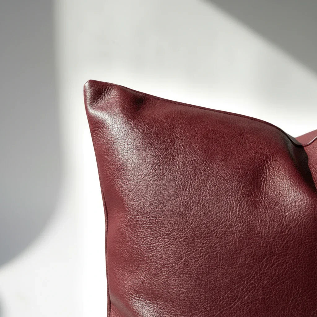 Corner detail of burgundy faux leather pillow cover showing clean stitching and smooth finish