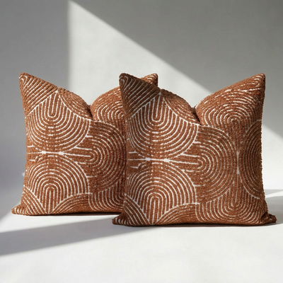 Set of 2 tufted burnt orange chenille pillow covers with geometric swirl pattern on white surface