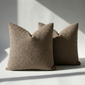Set of 2 brown boucle throw pillow covers on white surface with soft natural light