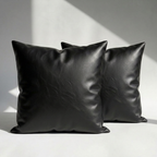 Set of 2 black vegan leather throw pillow covers on white surface – smooth grained texture