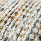 Close-up of multicolor chenille tufted pillow cover showing dense looped fringe weave in cream, brown, gold, and teal