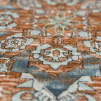 Close-up of woven Persian boho rug surface showing terracotta and blue floral medallion detail and distressed texture