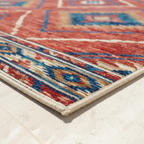 Corner detail of southwestern rug showing serged cream edge and low-pile construction on tile floor