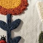 Macro detail of punch needle loop pile — mustard, rust, and navy floral motif on ivory cotton canvas pillow cover