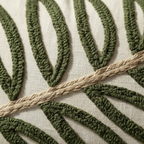 Close-up of forest green punch needle leaf embroidery detail on cream lumbar pillow cover