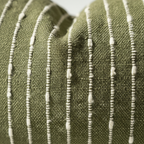 Close-up of jacquard woven boucle fabric showing raised cream stripe and dot texture on olive ground