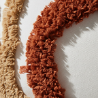 Macro detail of rust and caramel tufted loops on white cotton canvas pillow cover