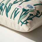 Close-up of raised embroidery detail on cream cotton canvas pillow cover showing teal botanical stems and multicolor flowers