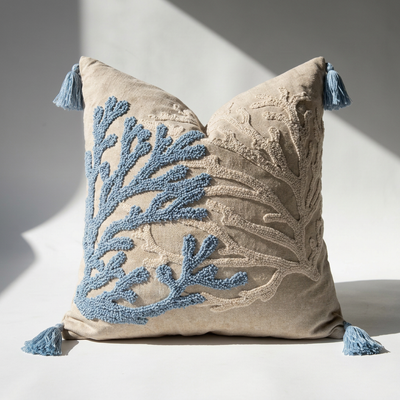 Handcrafted punch needle cotton-linen throw pillow cover with dusty blue coral branch motif and corner tassels on natural beige ground