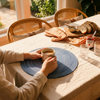 Blue woven round jute placemat on dining table with coffee cup and natural light – Larissa Home Decor