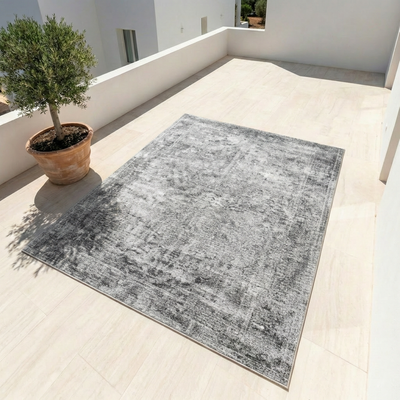 Gray vintage distressed area rug on light tile patio with olive tree — machine washable non-slip boho decor