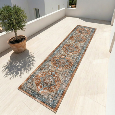 Persian boho vintage runner rug in terracotta rust and dusty blue, shown in a bright outdoor terrace setting
