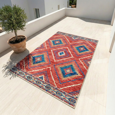 Southwestern geometric area rug in terracotta red and teal with Aztec diamond pattern on outdoor terrace