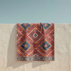 Southwestern Aztec geometric rug in red and blue with diamond medallion design, draped view