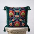 Handcrafted green velvet throw pillow cover with embroidered floral botanical panel and corner tassels on stone pedestal