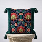 Handcrafted green velvet throw pillow cover with embroidered floral botanical panel and corner tassels on stone pedestal